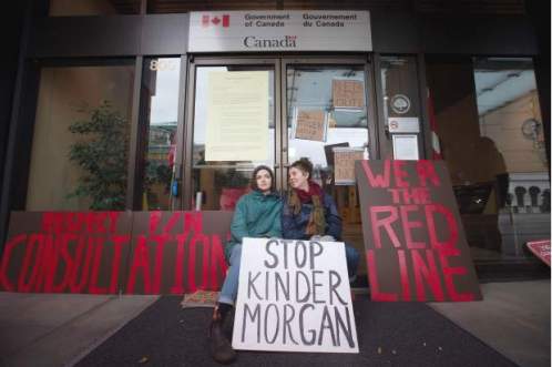  Two women sit outside the offices of the National Energy Board after locking themselves to the doors by placing bike locks around their necks, to protest the Kinder Morgan Trans Mountain Pipeline expansion, in Vancouver, B.C., on Monday January 18, 2016.DARRYL DYCK / THE CANADIAN PRESS